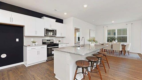Kitchen and island with white cabinets, quarts countertops, wood floors, and stainless steel appliances