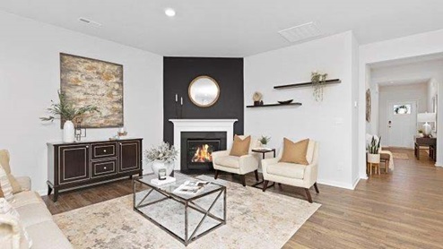 Modern open-concept living room with wood floors, and a fireplace, located beside kitchen