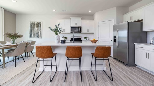 Kitchen and island with white cabinets, counters, subway tile backsplash and stainless steel appliances
