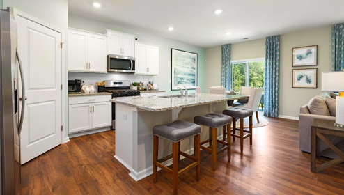 Kitchen with wood floors, island, and white cabinets