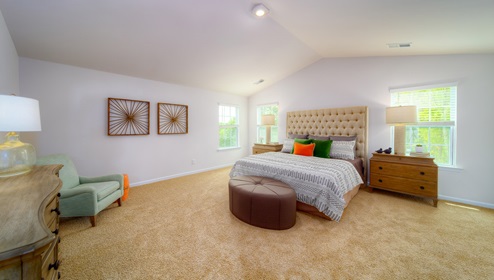 Primary carpeted bedroom with two windows