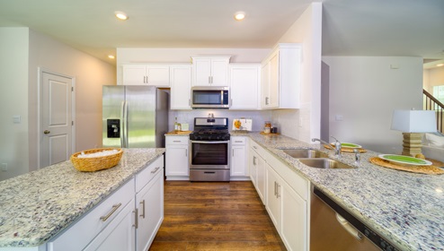 Kitchen with white cabinets, island, and kitchen appliances