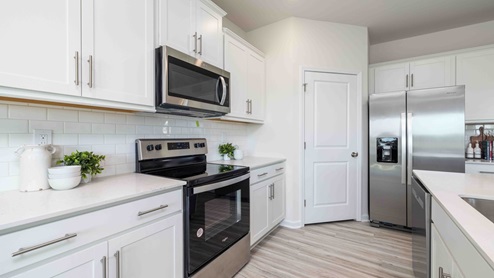 Kitchen and island with white cabinets, counters, subway tile backsplash and stainless steel appliances