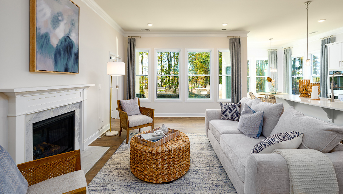 Open living room with wood floors, three windows, and fireplace