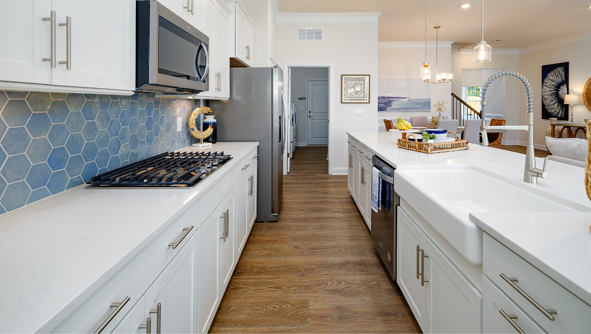 Kitchen and island with wood floors, white cabinets and counters, stainless steel appliances, and seating at island bar