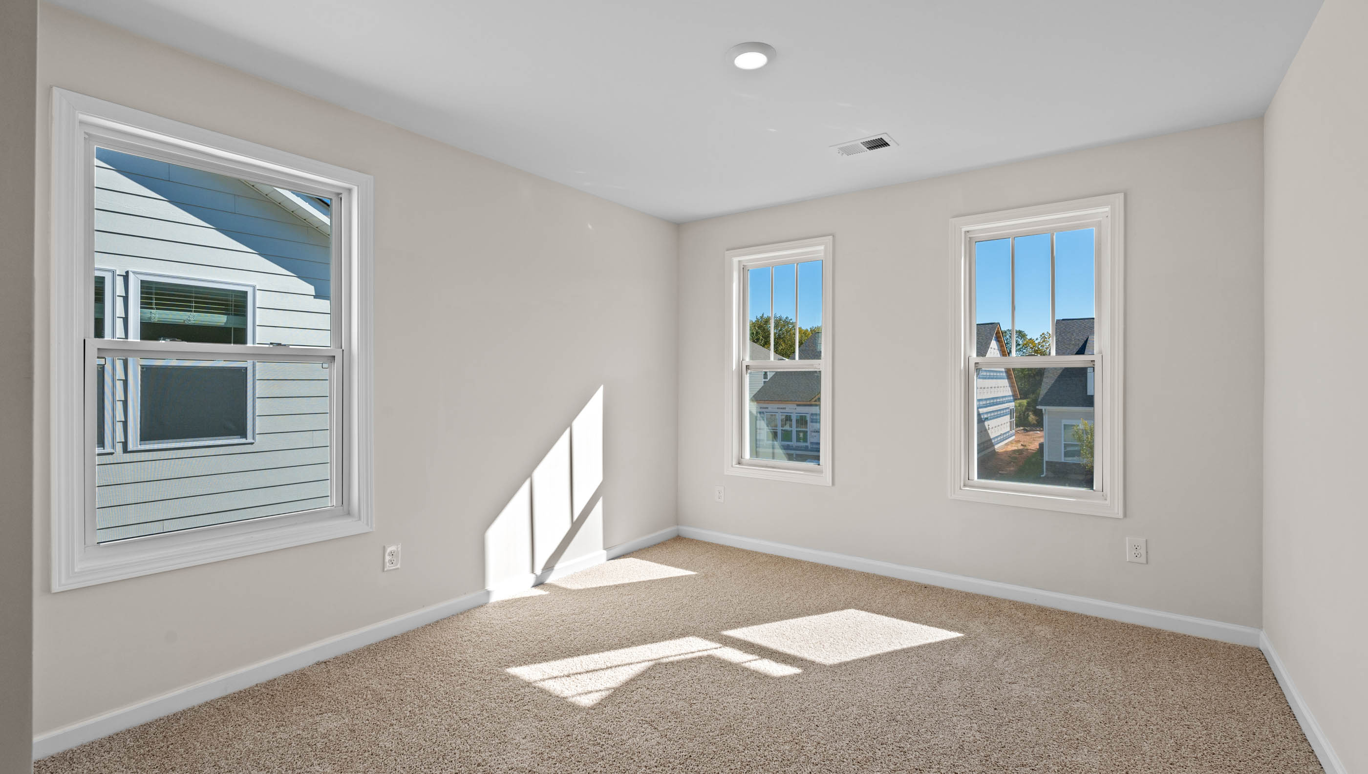 Carpeted bedroom with three large windows