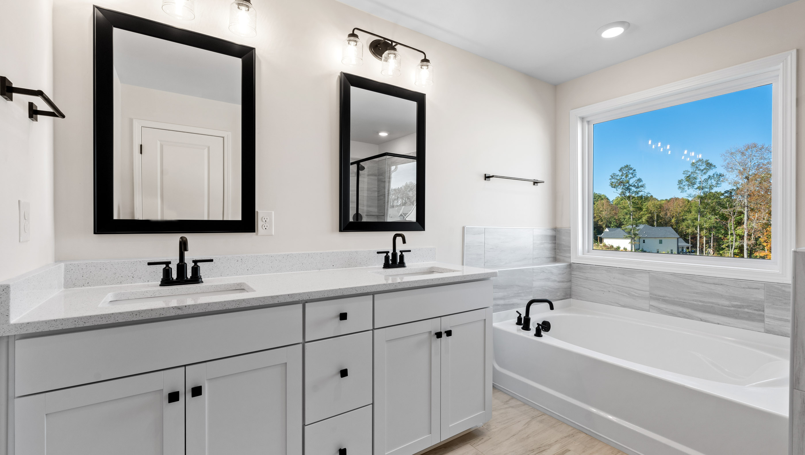 Primary bathroom with white cabinets, bathtub, and glass door shower