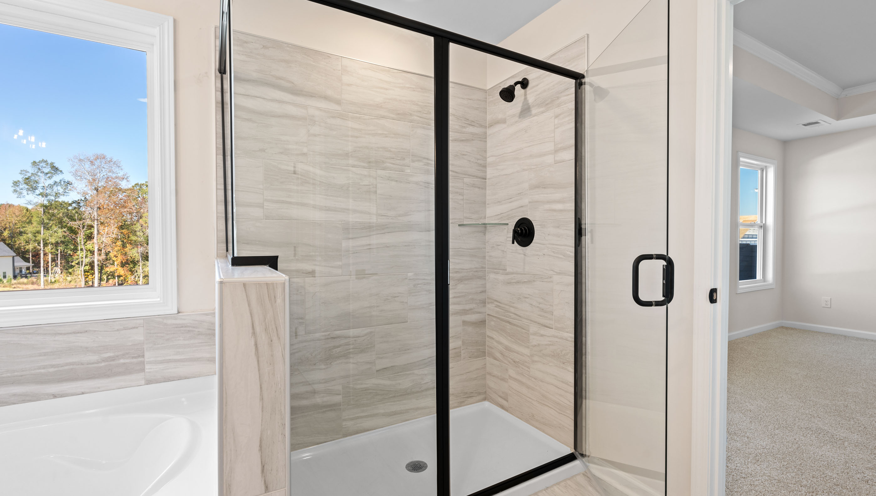Primary bathroom with white cabinets, bathtub, and glass door shower