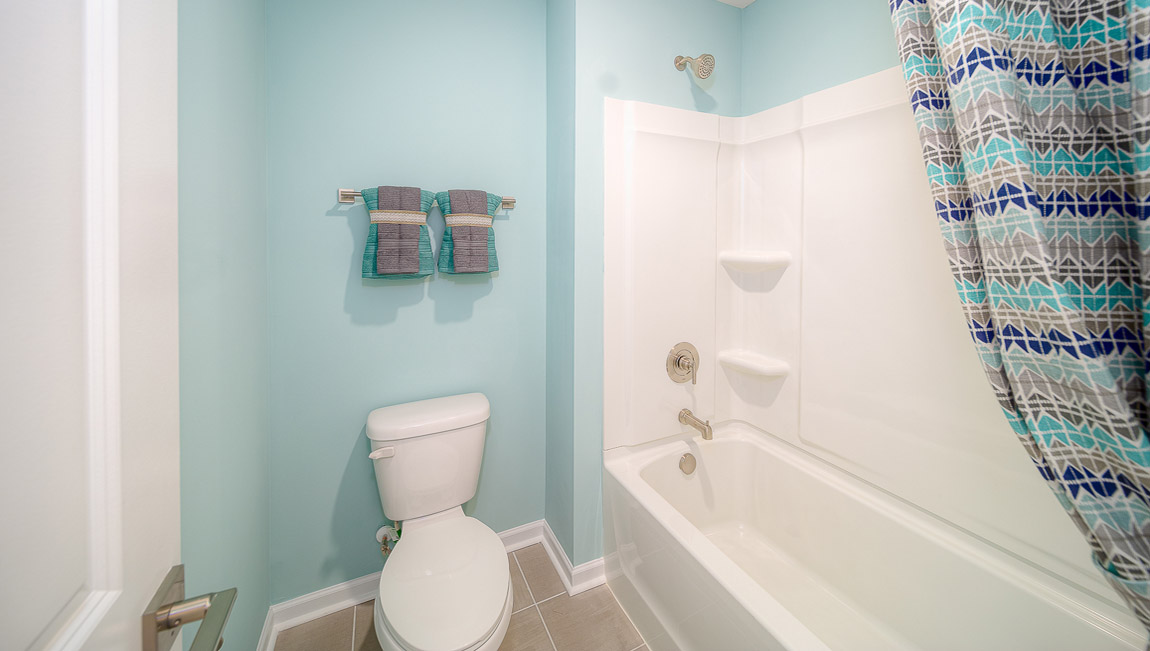 Bathroom with double sinks, white cabinets, and separate door to bathtub and toilet