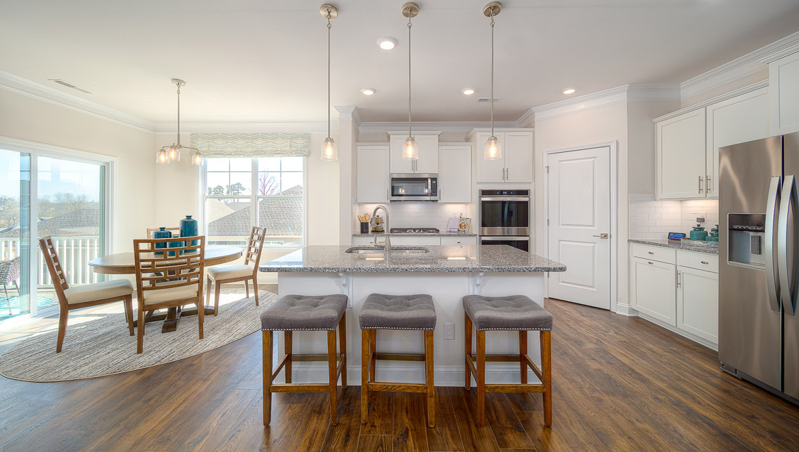 Kitchen and island with wood floors, white cabinets, breakfast area on island bar, and stainless steel appliances
