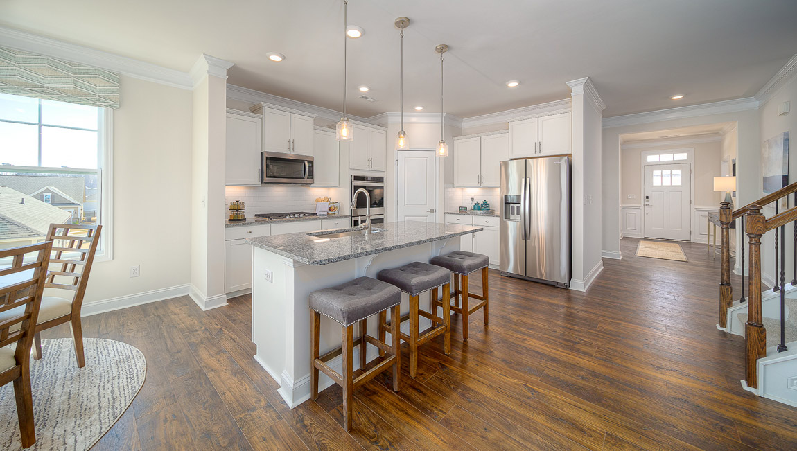 Kitchen and island with wood floors, white cabinets, breakfast area on island bar, and stainless steel appliances