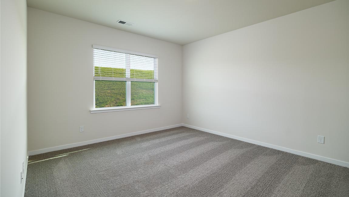 Carpeted primary bedroom with large window and ceiling fan