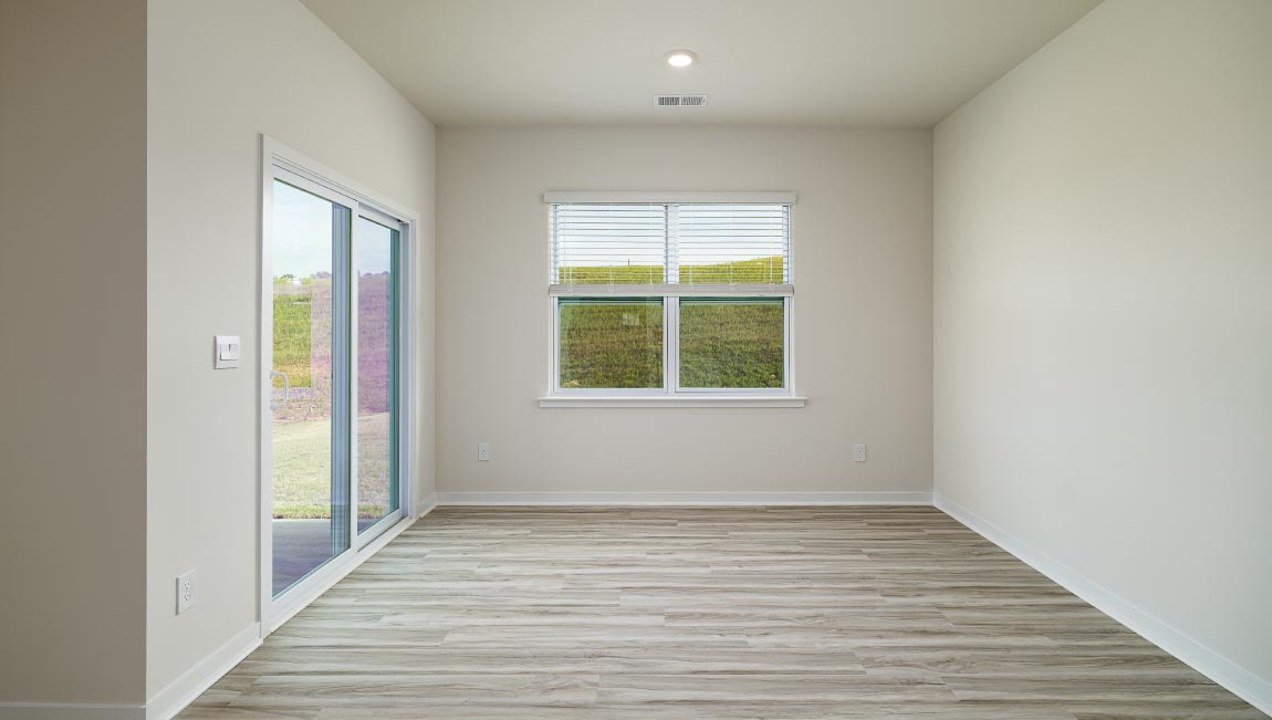 Dining area beside kitchen and living room with large windows and sliding glass back door