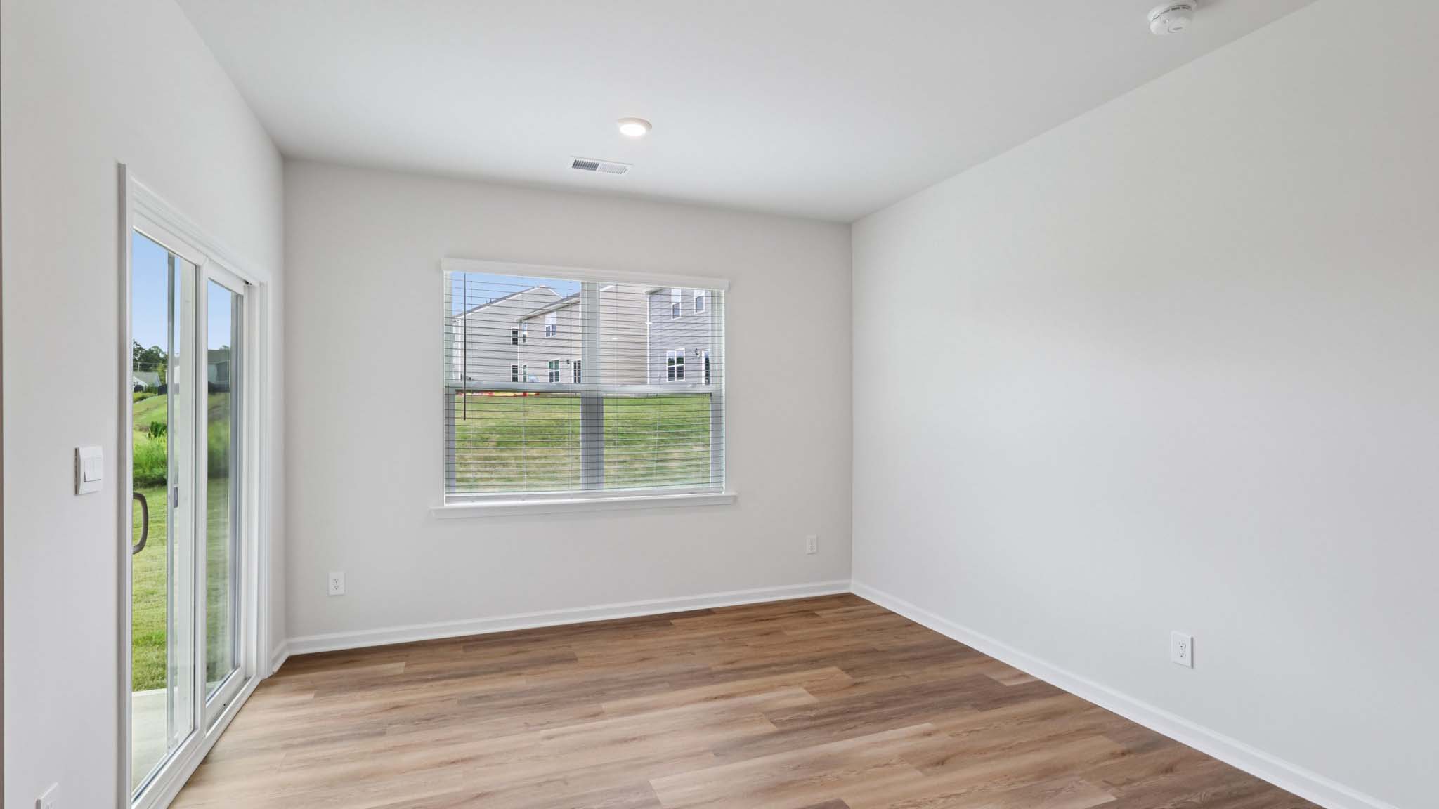 Dining area beside kitchen and living room with large windows and sliding glass back door