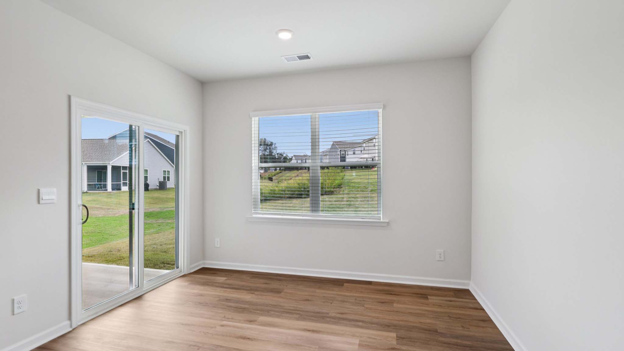 Dining area beside kitchen and living room with large windows and sliding glass back door