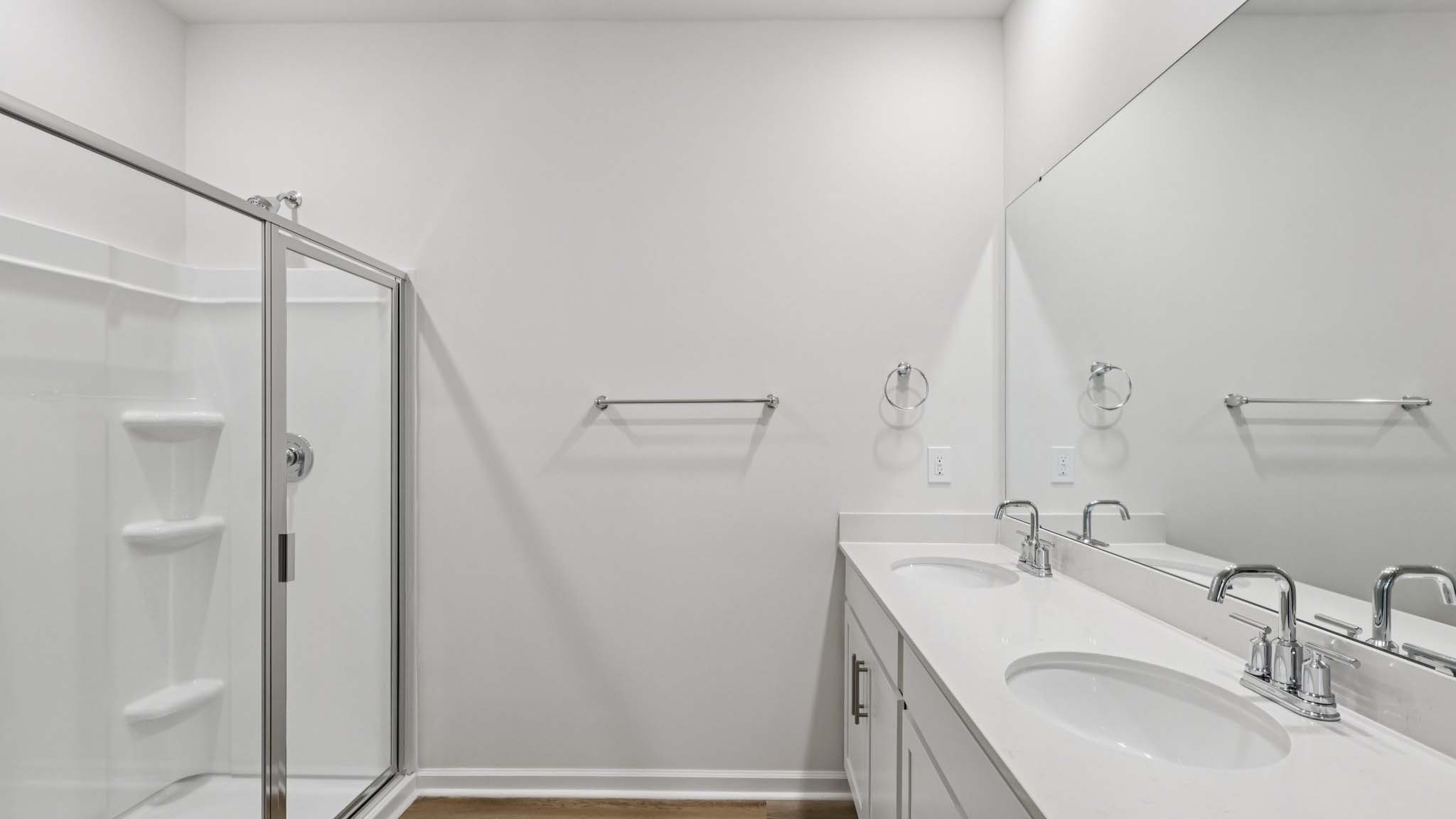 Bathroom with white cabinets and counters, double vanity, and glass door shower