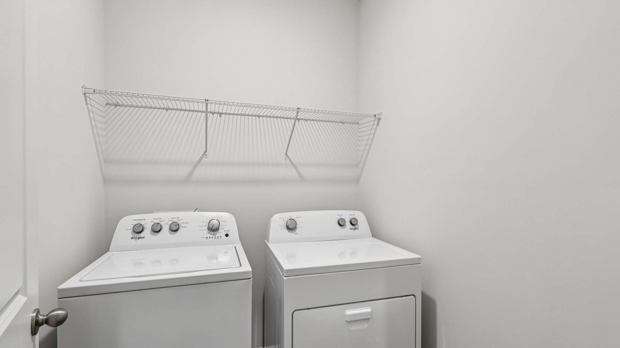 Laundry room with storage and hanging racks above machines