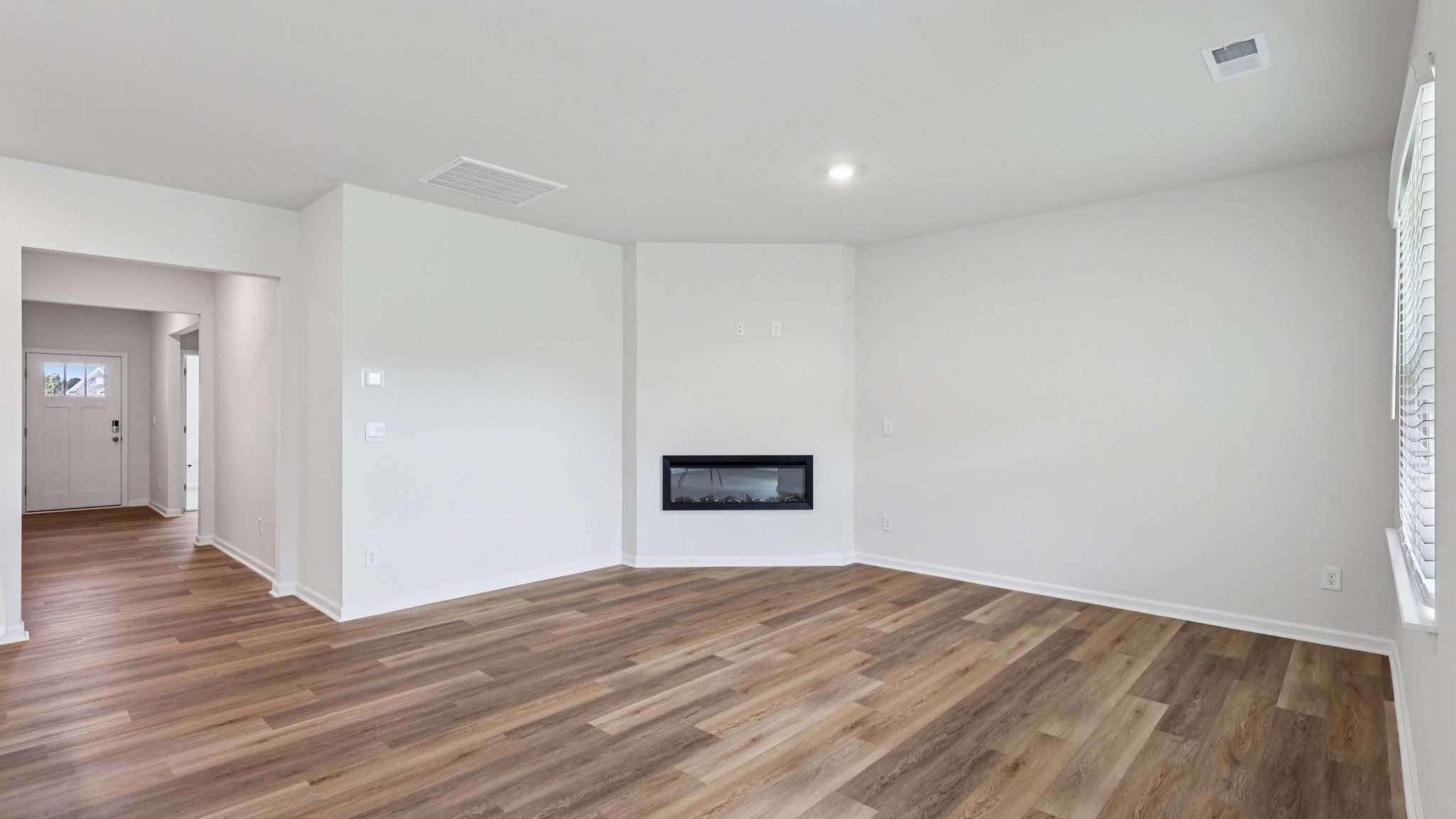 Open living room with ceiling fan and large window, kitchen and dining room in view