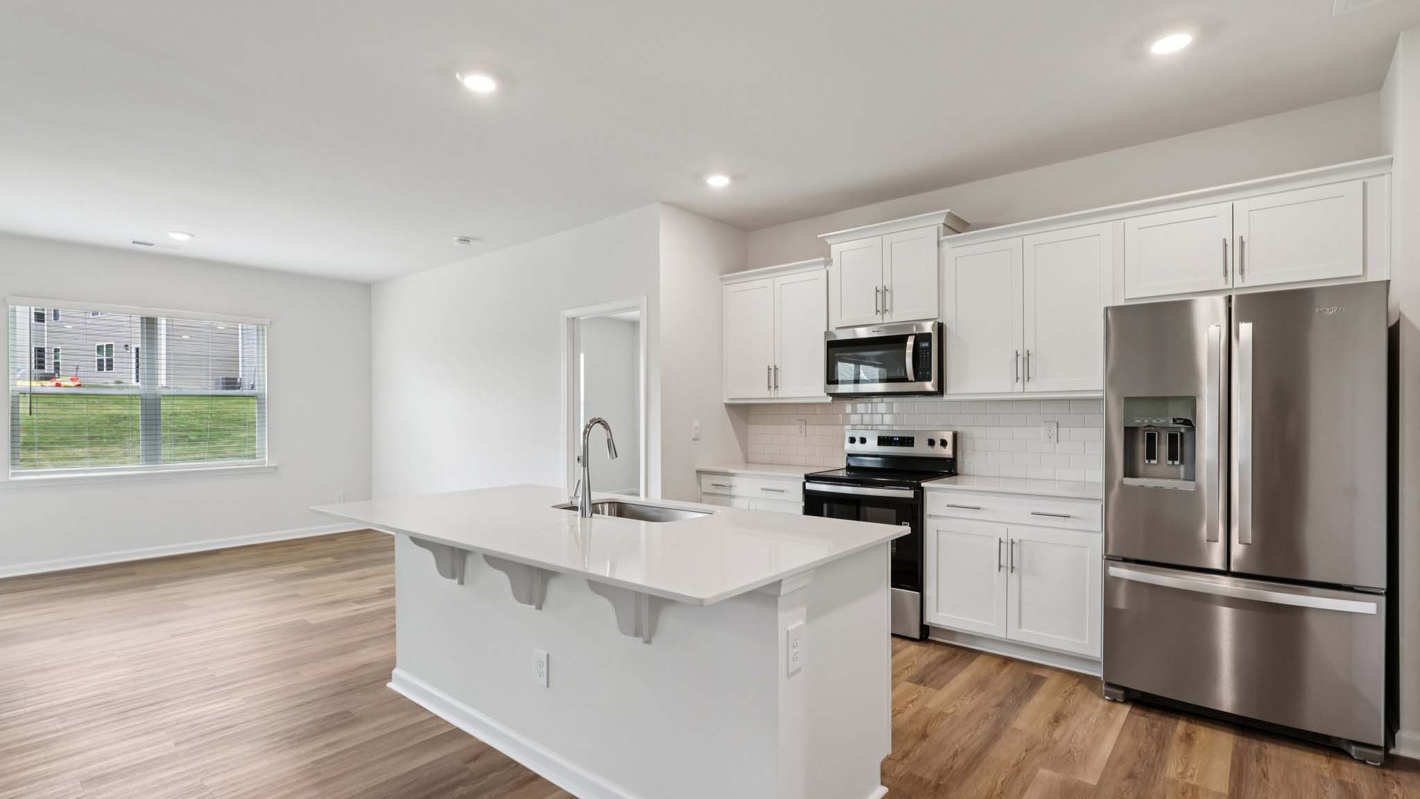 Kitchen and island with white cabinets, breakfast area at island, and stainless steel appliances