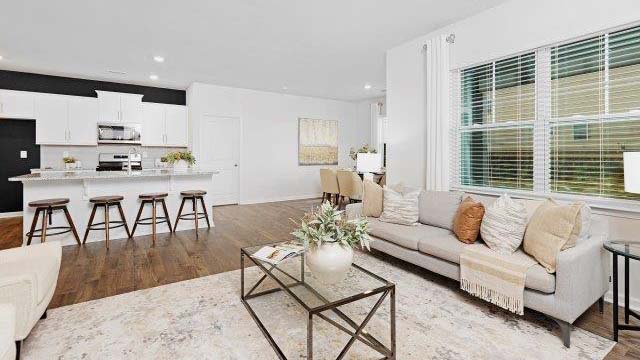 Open living room with ceiling fan and large window, kitchen and dining room in view