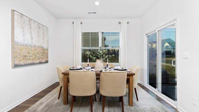 Dining area beside kitchen and living room with large windows and sliding glass back door