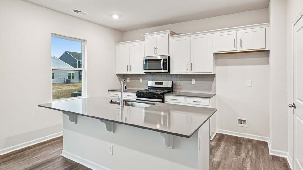 Kitchen and island with white cabinets and counters, vinyl floors and stainless steel appliances