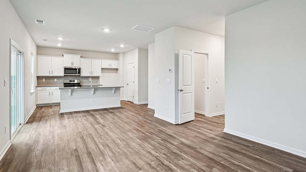 Kitchen and island with white cabinets and counters, vinyl floors and stainless steel appliances