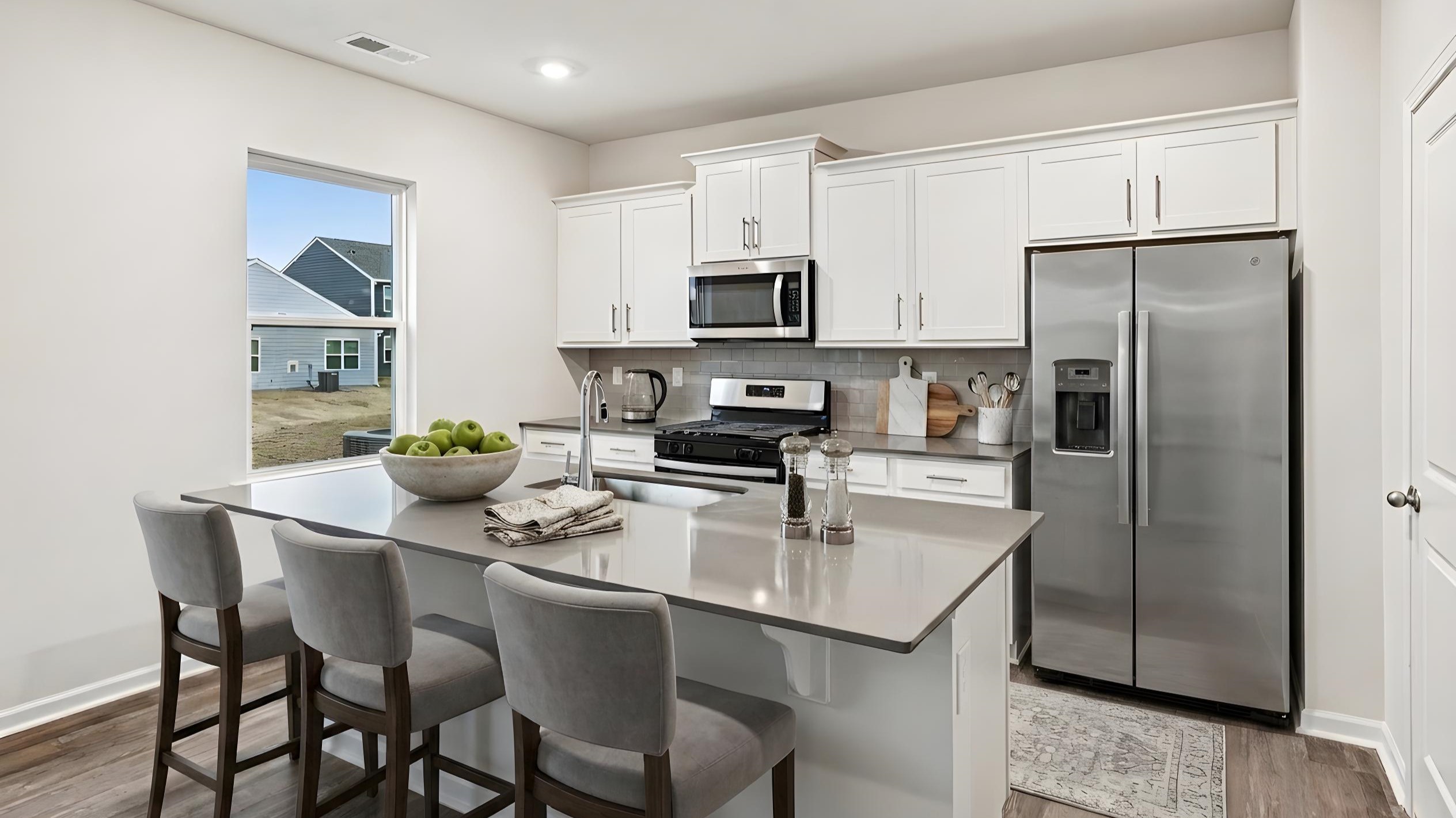 Kitchen and island with white cabinets and counters, vinyl floors and stainless steel appliances