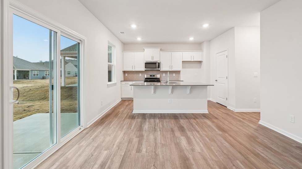 Kitchen and island with white cabinets and counters, vinyl floors and stainless steel appliances