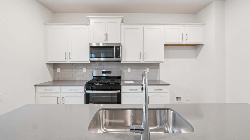 Kitchen and island with white cabinets and counters, vinyl floors and stainless steel appliances