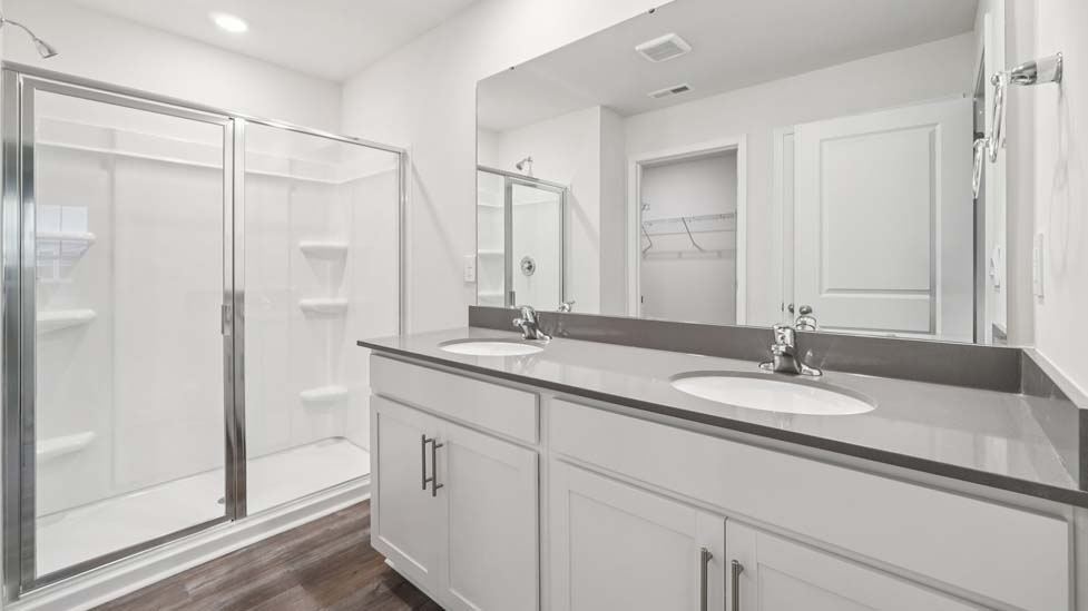 Primary bathroom with double vanity and glass door shower