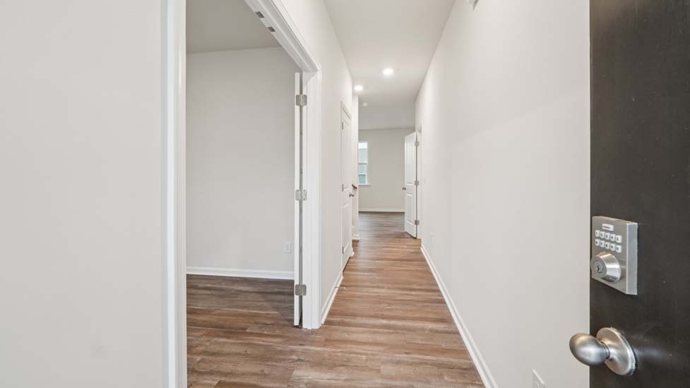 Welcoming foyer from front door with view of hallway and flex space