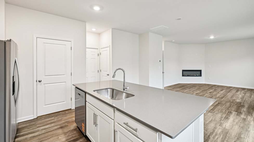 Kitchen and island with white cabinets and counters, vinyl floors and stainless steel appliances