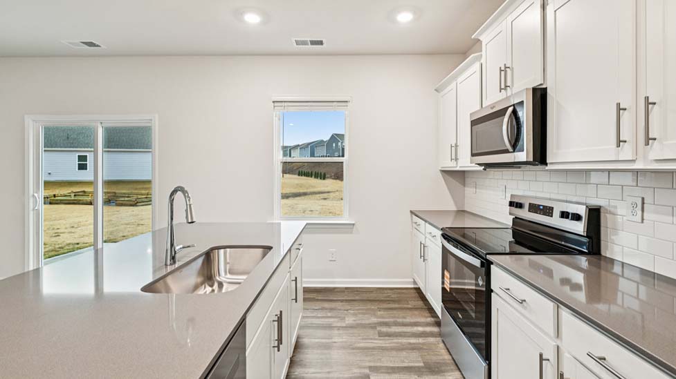 Kitchen and island with white cabinets and counters, vinyl floors and stainless steel appliances