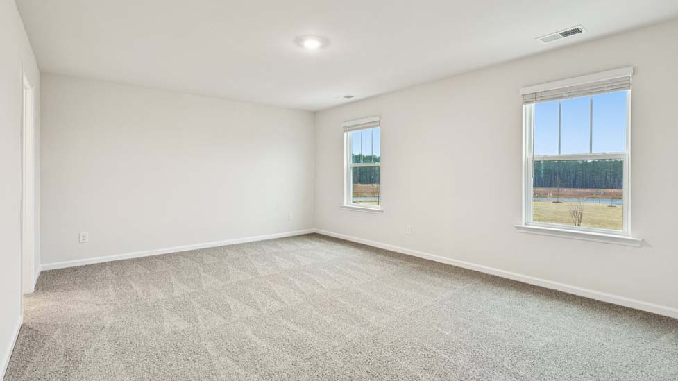Primary bedroom with carpet and two large windows
