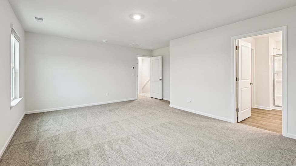 Primary bedroom with carpet and two large windows