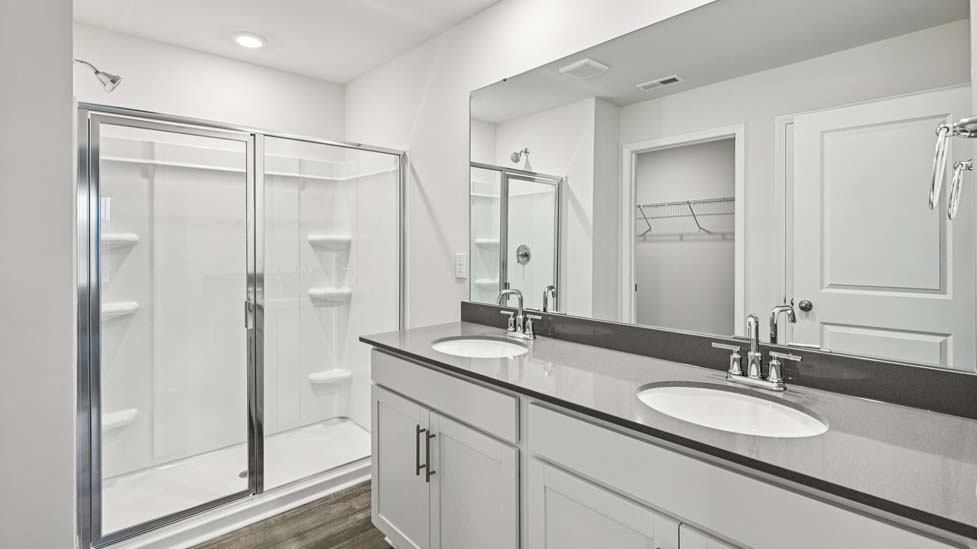 Primary bathroom with double vanity and glass door shower