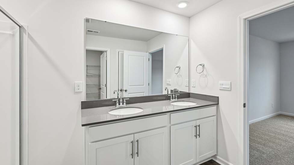 Primary bathroom with double vanity and glass door shower