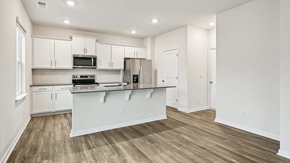 Kitchen and island with white cabinets and counters, vinyl floors and stainless steel appliances
