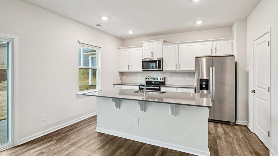 Kitchen and island with white cabinets and counters, vinyl floors and stainless steel appliances