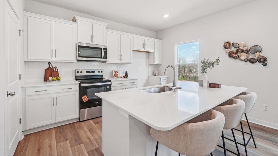kitchen and island with white cabinets, wood floors and stainless steel appliances