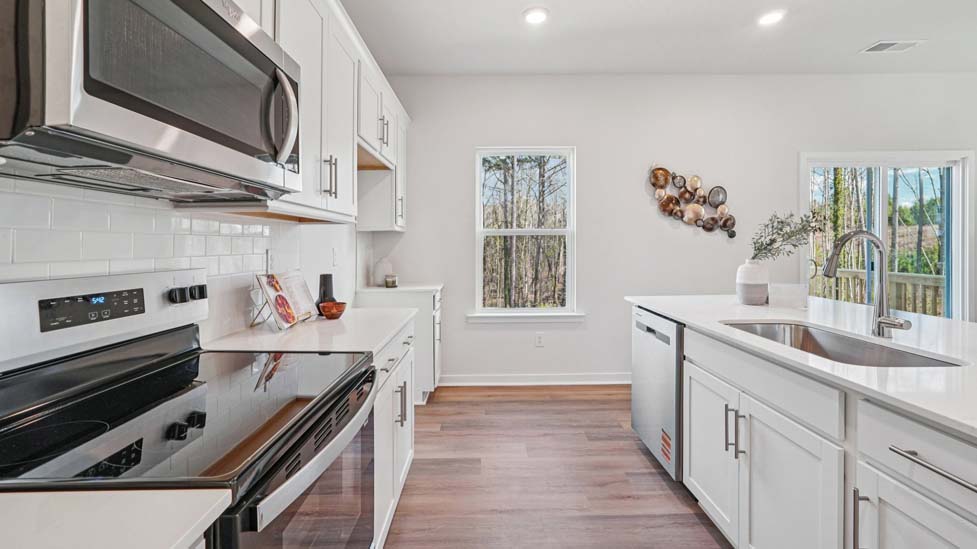 kitchen and island with white cabinets, wood floors and stainless steel appliances