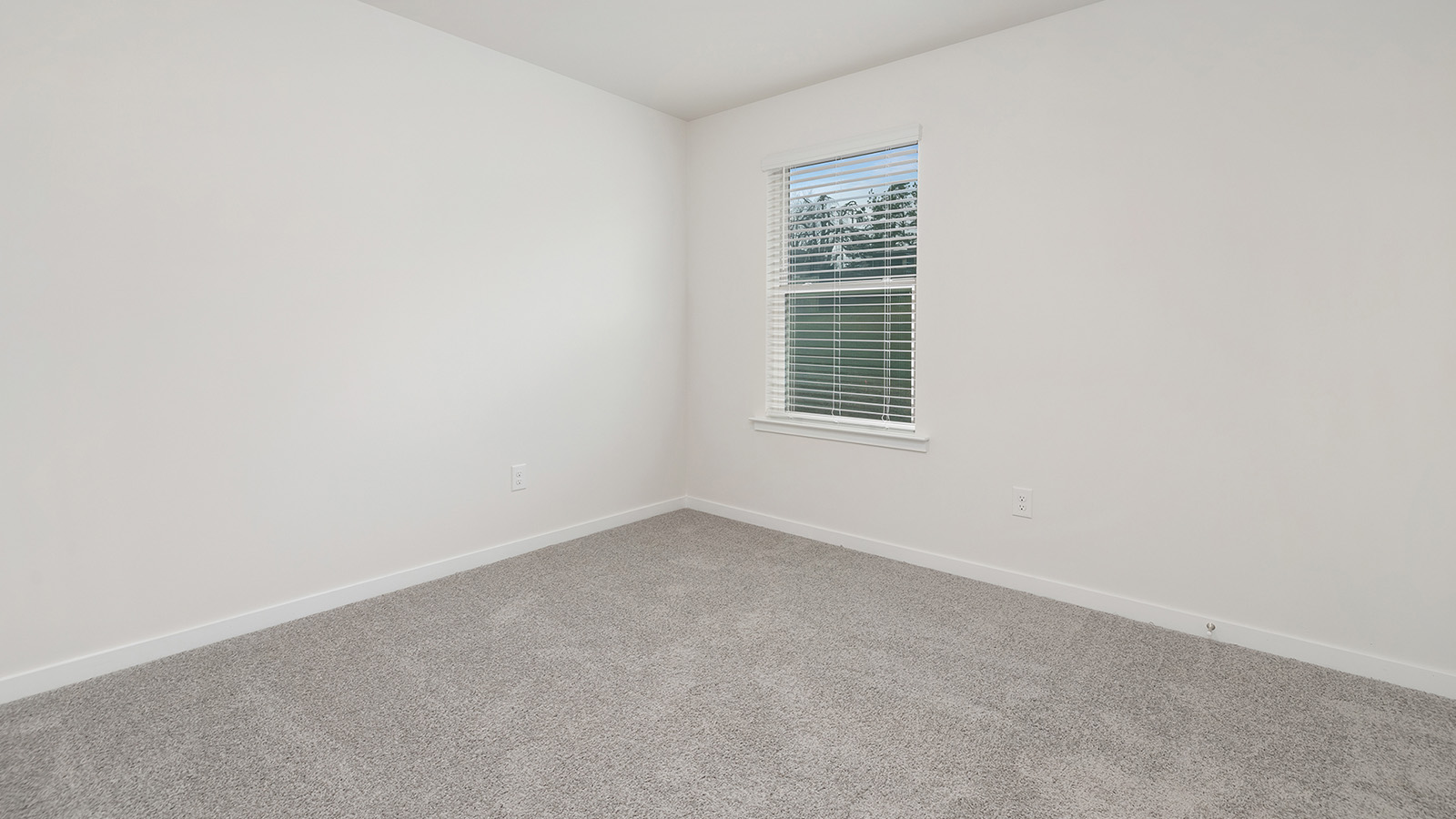 Model carpeted bedroom with small window