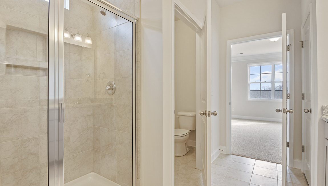 Primary bathroom with white cabinets and counters, view of closet