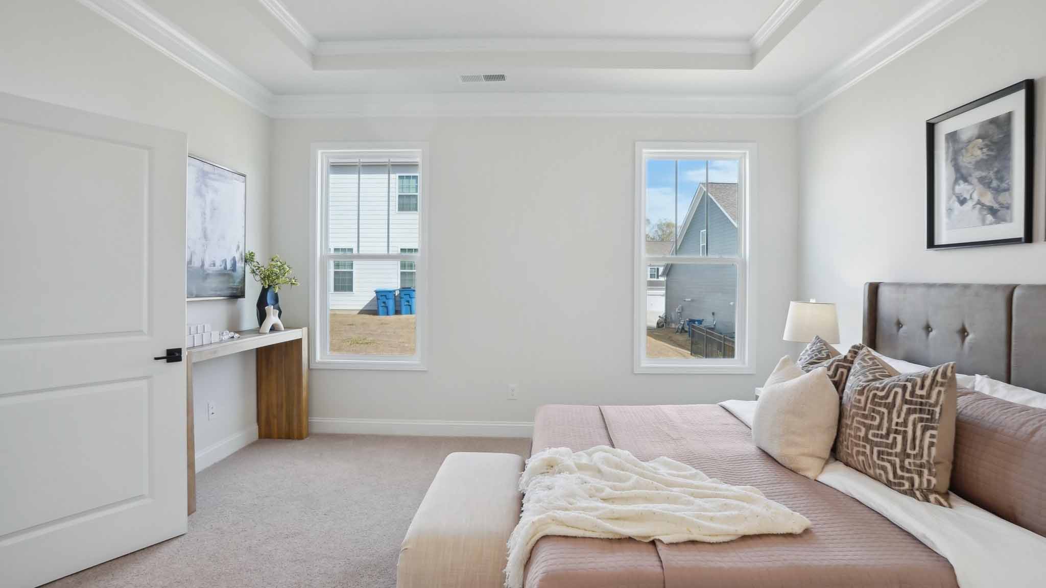 Primary bedroom with wood floors, and two large windows