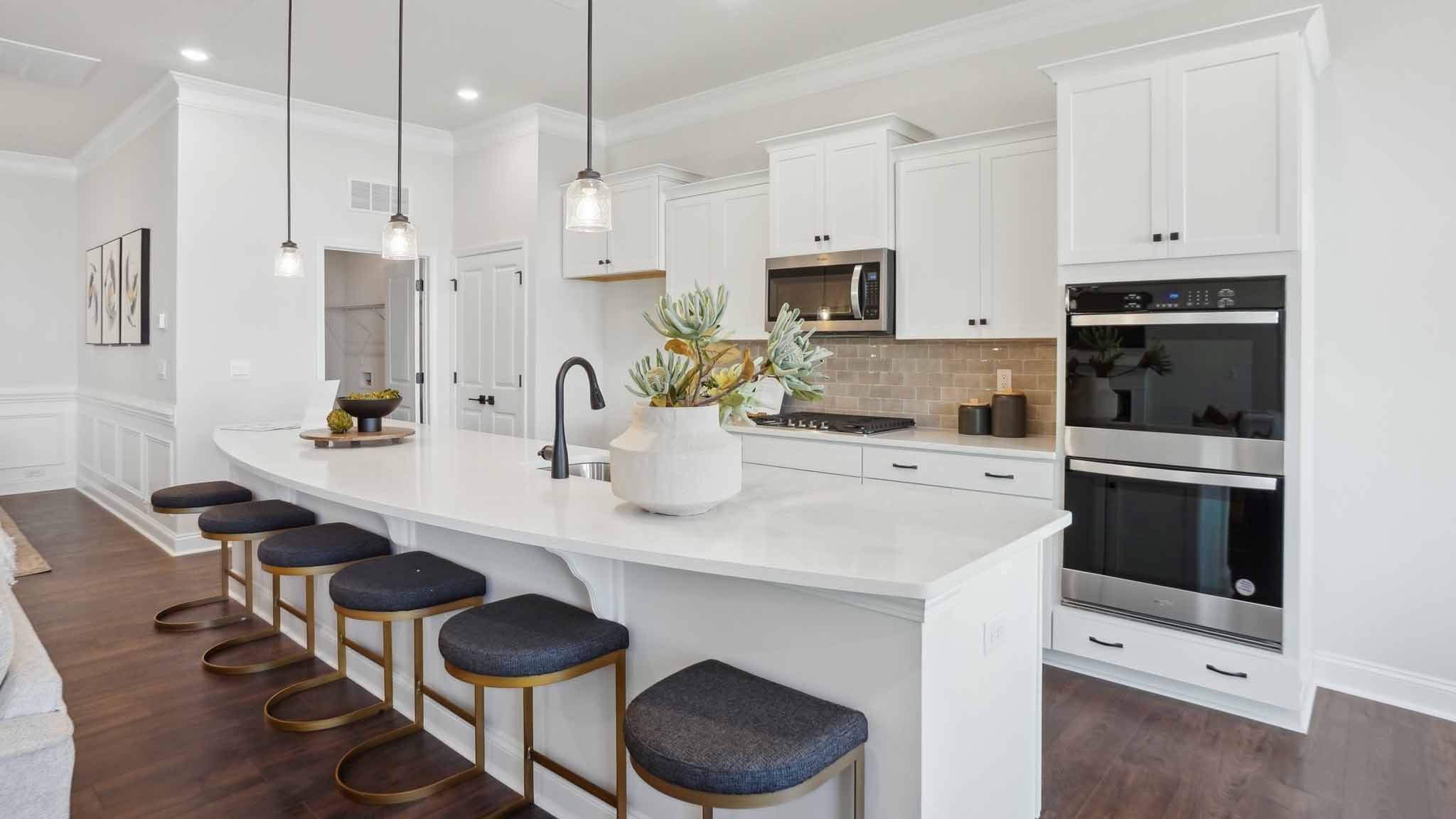 Kitchen and island with wood floors, white cabinets and counters, stainless steel appliances, and seating at island bar