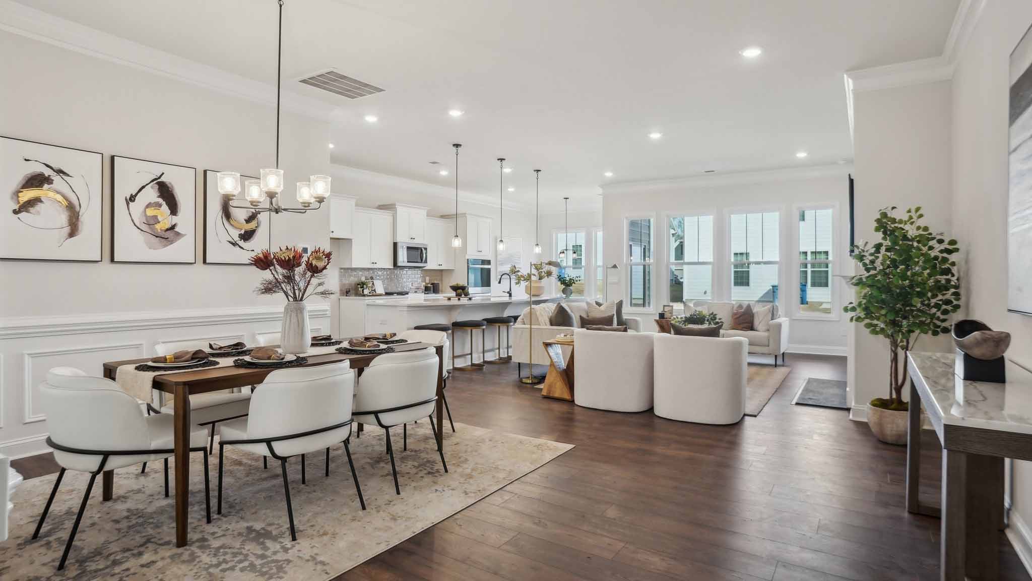 Kitchen and island with wood floors, white cabinets and counters, stainless steel appliances, and seating at island bar