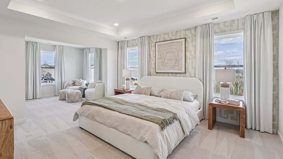 Primary bedroom with beige carpet, ceiling fan and large window