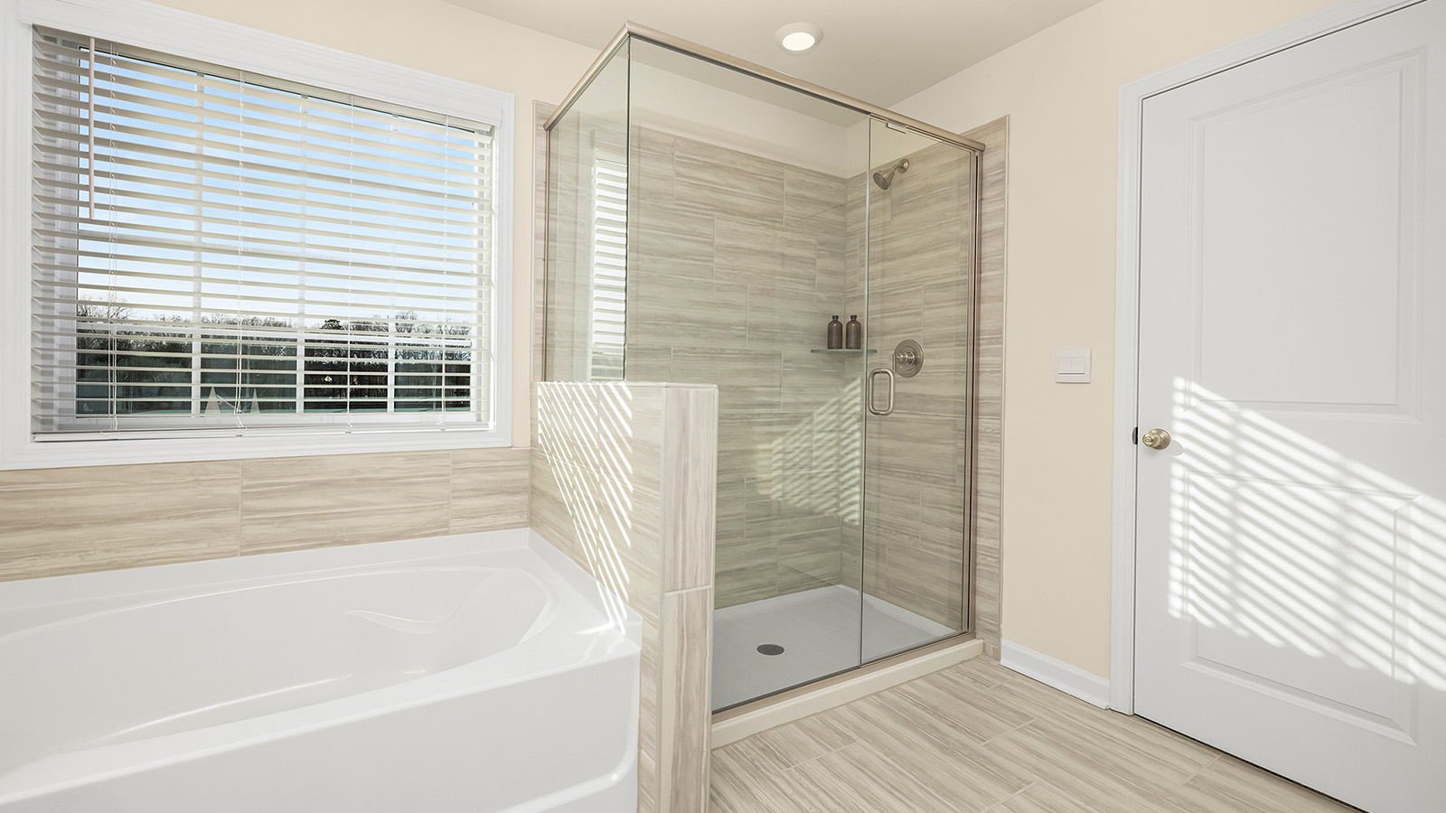 primary bathroom with double sinks, separate tub and glass door shower