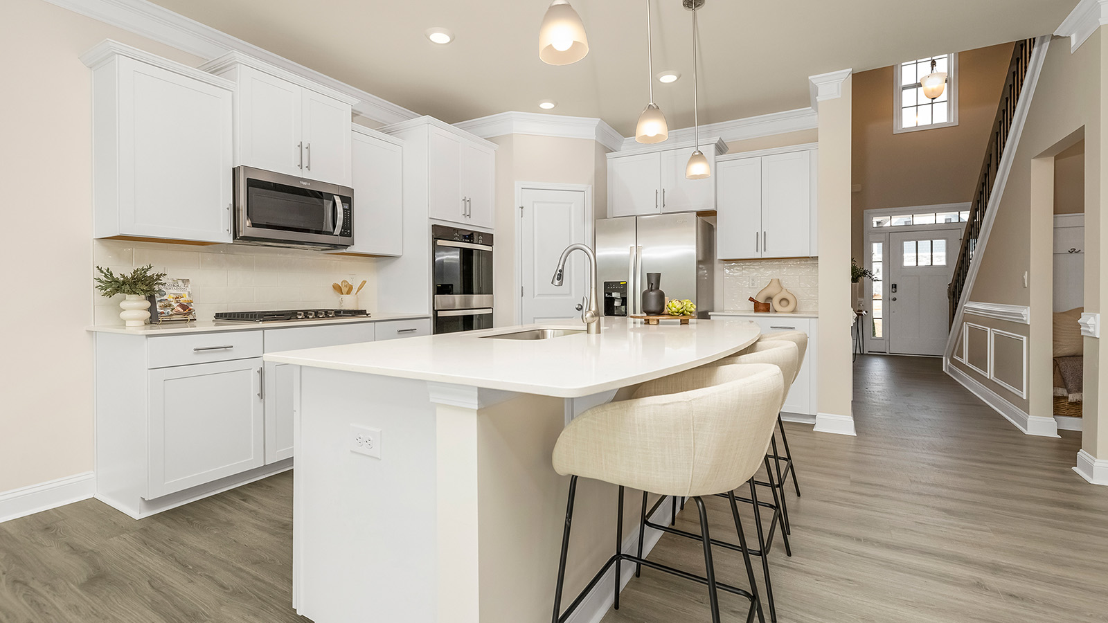 Open concept kitchen with large island, white cabinets and countertops, stainless steel appliances